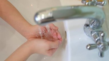 Musluktan akan suyun üst görüntüsü çocukların eline dökülüyor. Temiz el kavramı