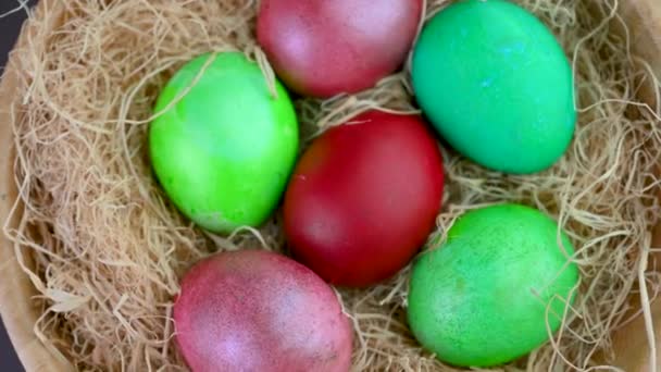 复活节装饰在桌上 许多五彩缤纷的假日彩蛋放在木碗里的干草上 轮调360 — 图库视频影像