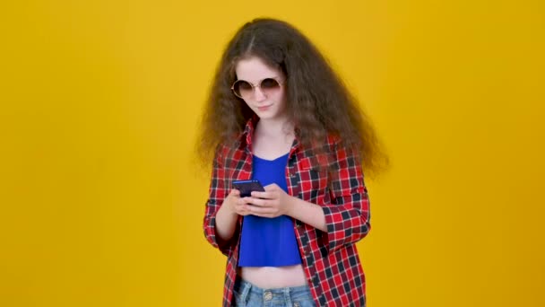 Menina Feliz Nova Com Cabelo Encaracolado Usando Óculos Usando Telefone — Vídeo de Stock