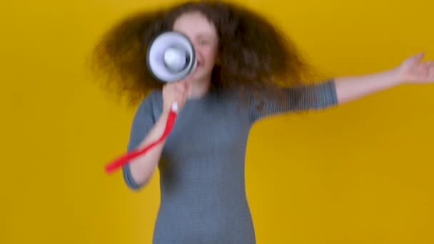 Sarı Arka Planda Megafonla Konuşan Kıvırcık Saçlı Mutlu Genç Kız — Stok video