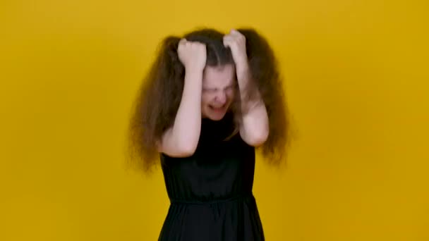 一个有着歇斯底里表情的小女孩 双手放在头上 背景是黄色的 女人强调要看着相机 人的情感概念 — 图库视频影像