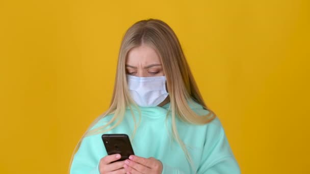 Portrait Young Girl Protective Mask Uses Smartphone Isolated Yellow Background — Stock Video