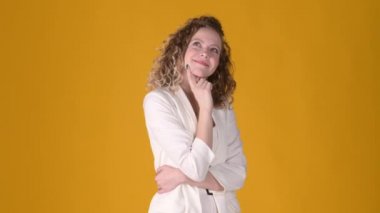 Kıvırcık saçlı genç ve çekici bir kız sarı stüdyo arka planında hayal kurarak etrafa bakıyor. Halk yaşam tarzı konsepti