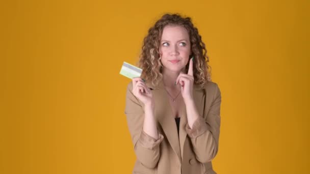 头发卷曲的快乐的小女孩拿着信用卡 有了一个很好的新主意 在黄色的工作室背景下说是的 人的生活方式概念 — 图库视频影像