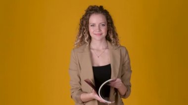 Stüdyonun sarı arka planında parlak bir dergide kıvırcık saçlı genç ve çekici bir kız. fikir arayışı