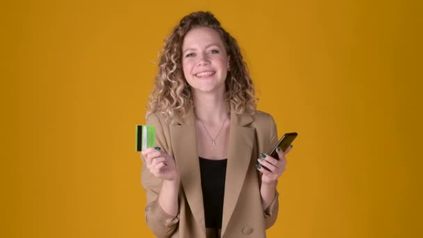 Jovem Alegre Expressivo Com Cabelo Encaracolado Usando Celular Segurar Cartão — Vídeo de Stock