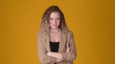 Sarı arka planda izole edilmiş, kıvırcık saçlı, gülümseyen ve kameraya bakan neşeli genç kadın portresi. İnsanlar samimi duygular, yaşam tarzı konsepti. Duygular.