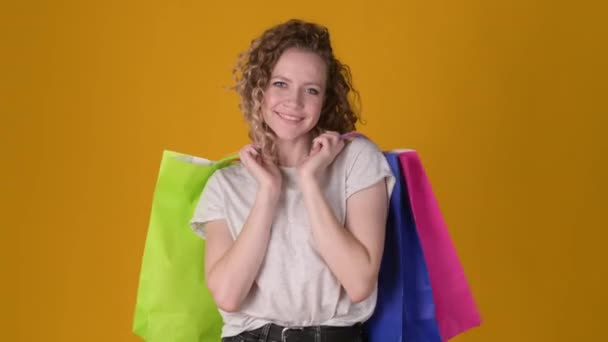 Glücklich Lächelnde Süße Frau Mit Lockigem Haar Hält Bunte Papiereinkaufstüten — Stockvideo