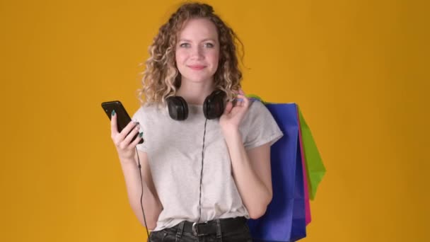 Portrait Happy Shopper Girl Curly Hair Headphones Holding Shopping Bags — Stock Video