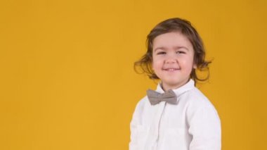 Gülen şirin bebek portresi. Komik küçük çocuk gülüyor ve sarı stüdyo arka planında izole edilmiş kameraya bakıyor. İnsanlar çocukluk yaşam tarzı konsepti
