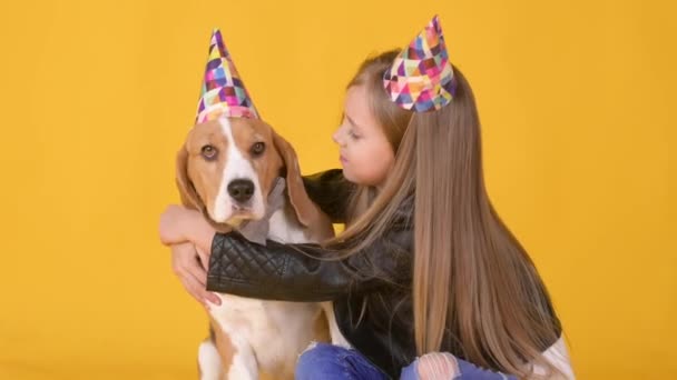 Маленькая Девочка Обнимает Свою Собаку Шляпе Отпраздновать День Рождения Жёлтом — стоковое видео