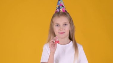 Doğum günü partisinde sarı stüdyo arka planında mutlu görünen şirin küçük bir kız. Tatil partisi doğum günü yaşam tarzı