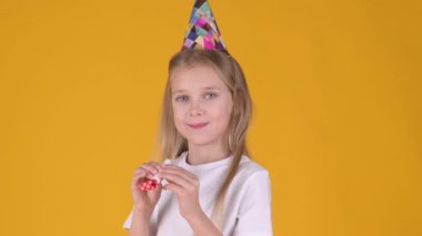 Doğum günü partisinde sarı stüdyo arka planında mutlu görünen şirin küçük bir kız. Tatil partisi doğum günü yaşam tarzı