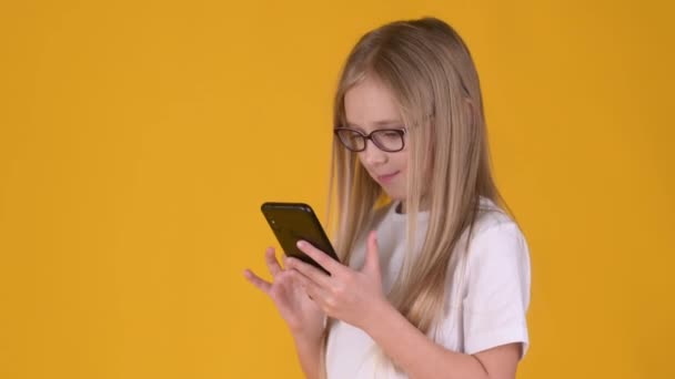 Χαριτωμένο Κοριτσάκι Ένα Λευκό Shirt Και Γυαλιά Χρησιμοποιώντας Ένα Κινητό — Αρχείο Βίντεο