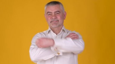 Neşeli yaşlı, gri saçlı bir adamın portresi gülümseyen ve sarı bir stüdyo arka planında kameraya bakan. Halk yaşam tarzı konsepti.