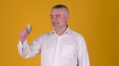 Neşeli, yaşlı, gri saçlı bir adam bankanın kredi kartına bakıp sarı stüdyo geçmişine karşı iyi niyet göstermiş. Halk yaşam tarzı konsepti.