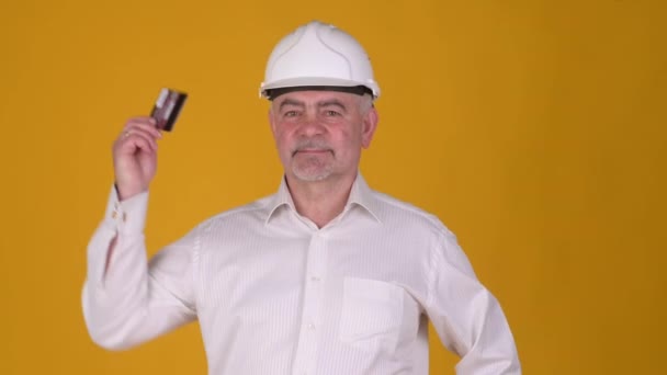 Glada Senior Man Byggare Hjälm Point Hand Kreditkort Mot Gul — Stockvideo