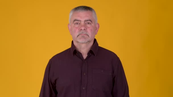 Portrét Staršího Šedovlasého Muže Vážnou Tváří Hledícího Kamery Pozadí Žlutého — Stock video