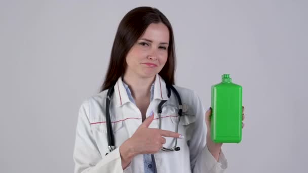 Médica Jovem Garrafa Segurando Uniforme Médica Com Gel Antibacteriano Aponta — Vídeo de Stock