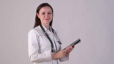 Tıbbi üniformalı gülümseyen kadın doktorun portresi beyaz arka planda izole edilmiş bir pano tutuyor. Sağlık çalışanları.