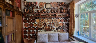 Geniş ve davetkar bir oturma odası. Konforlu bir kanepe ve çeşitli tabaklarla süslenmiş çarpıcı bir duvar.