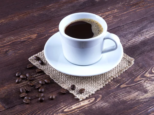 Café negro en una taza con café platillo — Foto de Stock