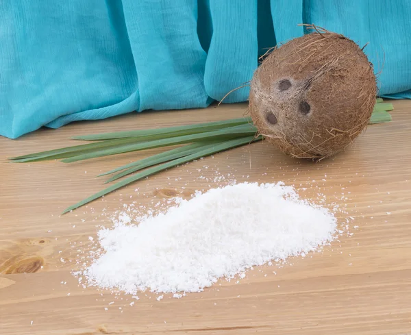 Coconut shavings, blue background, green leaves — Stock Photo, Image