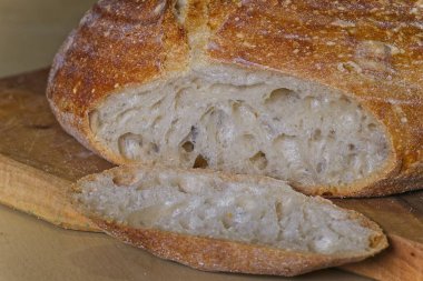 Bir somun ev yapımı ekmek, tahta tabakta, dilimlenmiş topuklu..