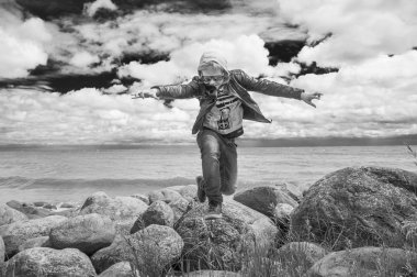 young boy is jumping off rocks  clipart
