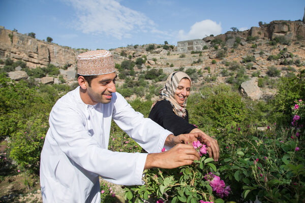 Omani man and a lady picking roses