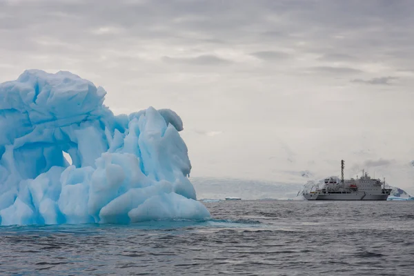 Синій айсберг і експедиційний човен — стокове фото