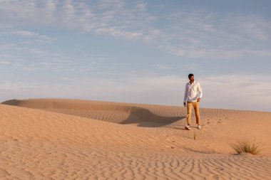 Yalnız adam gün doğumunda çölde yürüyor.