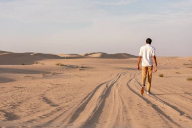 Yalnız adam gün doğumunda çölde yürüyor.