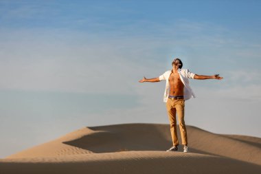 Yalnız adam gün doğumunda çölde eğleniyor.