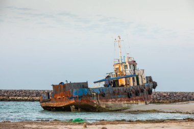 Eski terk edilmiş balıkçı teknesi Sharjah, Birleşik Arap Emirlikleri 'nde bir sahilde paslanıyor.