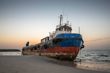 Eski terk edilmiş balıkçı teknesi Sharjah, Birleşik Arap Emirlikleri 'nde bir sahilde paslanıyor.