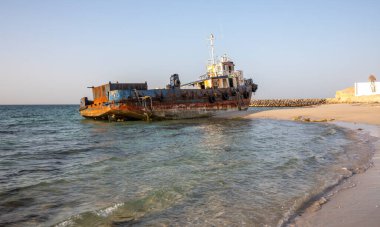 Eski terk edilmiş balıkçı teknesi Sharjah, Birleşik Arap Emirlikleri 'nde bir sahilde paslanıyor.