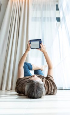 Evde kitap okuyan orta yaşlı bir kadın.