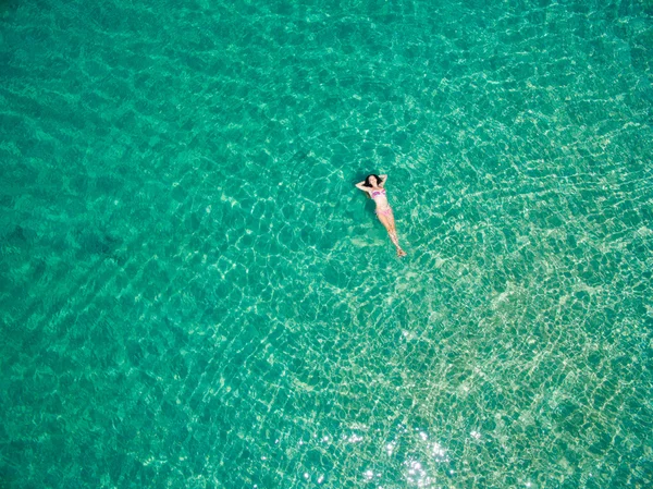 Vista superior da jovem mulher relaxando e nadando no mar azul-turquesa . — Fotografia de Stock