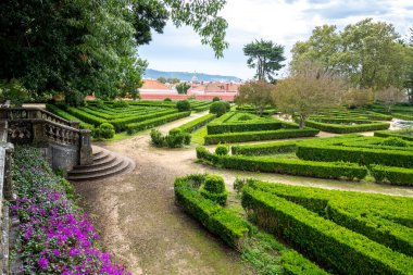 Belem, Lizbon, Portekiz 'de geometrik çitleri, patikaları ve ağaçları olan resmi bir bahçe manzarası.