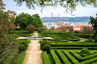 Geometrik çitler, Belem Lizbon 'da arka planda çatıları olan merkezi bir çeşmeye giden simetrik bahçe yolları oluşturur. Fotoğraf: 4 Kasım 2025.
