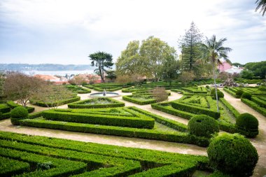 Belem, Lizbon, Portekiz 'de çeşmeli, palmiye ağaçları ve geometrik çit desenli resmi bir bahçe.
