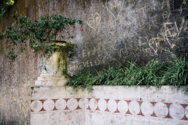 Portekiz 'in Sintra, Lizbon Bölgesi' nde 16 Ekim 2025 'te etrafı yeşilliklerle çevrili karmaşık mavi ve turuncu Portekiz fayansları ve yontulmuş meleklerle dolu taş çeşme..