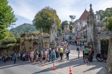 16 Ekim 2025 'te Portekiz' in Sintra şehrindeki Quinta da Regaleira malikanesinin girişinde taş mimari ve kale duvarlarıyla turist kalabalığı toplandı..