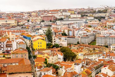 Lizbon Portekiz Aralık 05, 2025. Geniş bir yamaç manzarası, Lizbon şehir merkezindeki yoğun konut binalarını bulutlu gün ışığı altında gösteriyor..