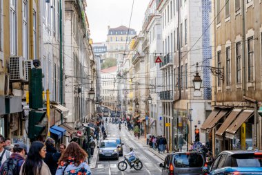 Lizbon Portekiz Aralık 05, 2025. Yokuş aşağı görüntüsü Lizbon 'daki tarihi binalar arasındaki trafik yayaları ve tramvay altyapısını gösteriyor.