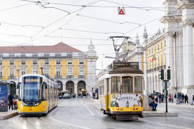Lizbon Portekiz Aralık 05, 2025. Modern bir tramvay ve tarihi bir tramvay şehir meydanında yan yana durur..