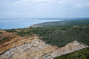Sesimbra Portekiz 25 Aralık 2025. Cabo Espichel yakınlarındaki Atlantik kıyısı boyunca katmanlı kaya kayalıkları ve kıyı bitki örtüsü uzanıyor.