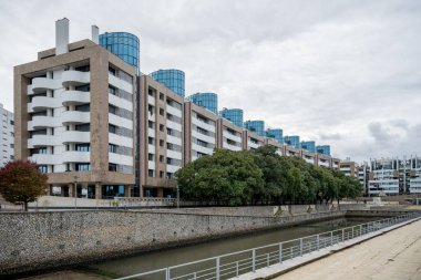 Lizbon Portekiz 18 Aralık 2025. Çağdaş Lizbon bölgesinde ağaçlarla ve yaya geçitleriyle modern yerleşim yerleri bir şehir kanalı oluşturur..