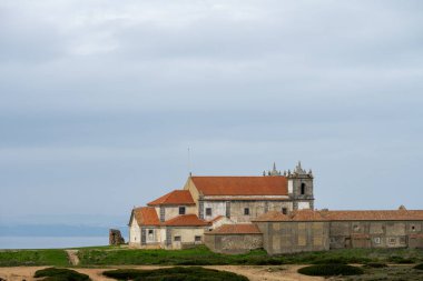 Cabo Espichel 'deki Atlantik Okyanusu' na bakan engebeli sahil kayalıklarının üzerinde taş sığınak binaları duruyor..